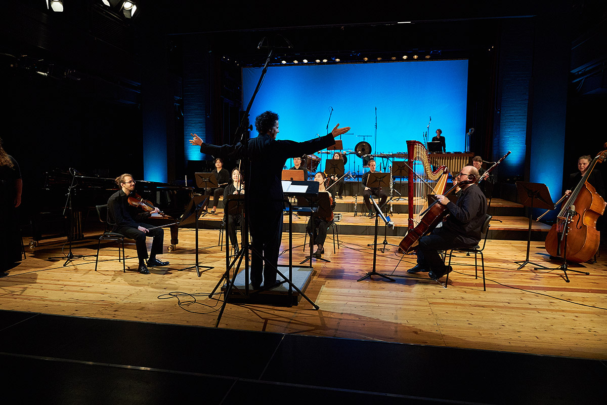 Hochschulprofessor und Studierenden-Ensemble auf einer Bhne nach beendigtem Konzert